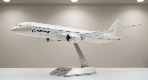 A museum-tier 1:200 scale diecast model of a Boeing 787-9 Dreamliner passenger aircraft finished in immaculate aerodynamic pearl white livery with rake wingtips. Posed gracefully on a brushed metallic display support with studio gallery lighting emphasizing realistic turbofan engine nacelles and subtle panel outlines.